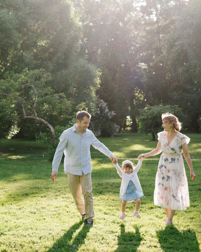 Mother and dad is holding their small daughter in the park 