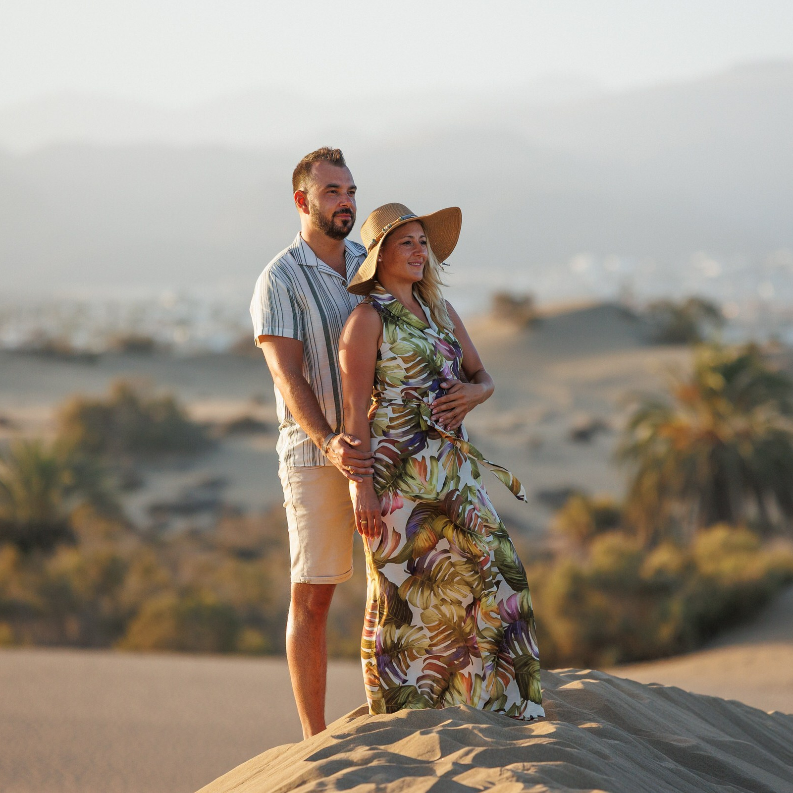 A man and a woman stand together on a sandy dune, surrounded by desert landscape Photoshoot Meloneras