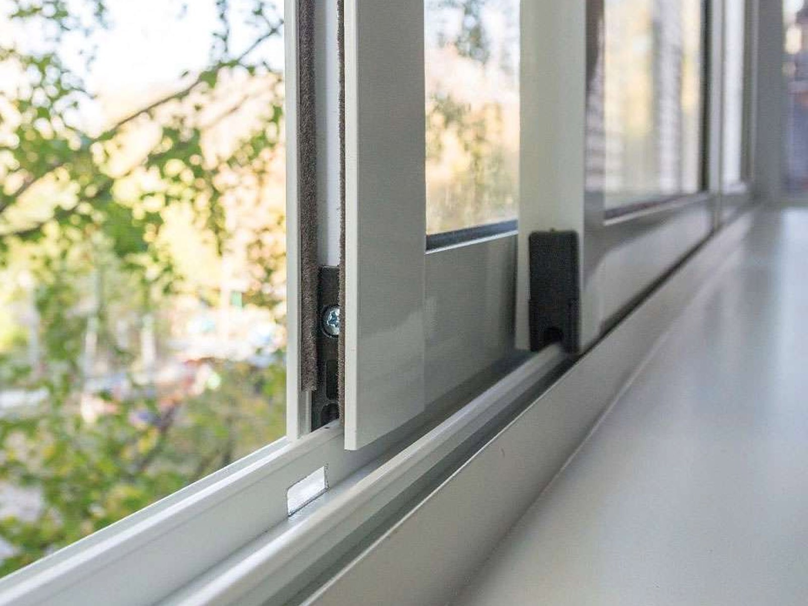 Балкон, оборудованный в верхней части раздвижной системой из холодного алюминия белого цвета.