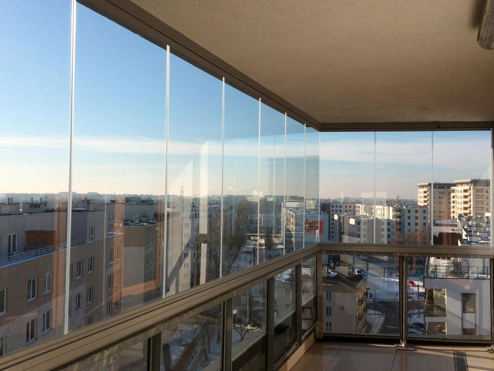 Большой балкон с выполненным безрамным остеклением и открывающейся панорамой на город с высоты 8-го этажа.