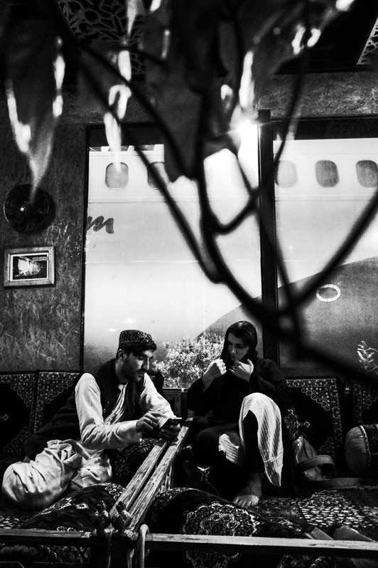 A young Afghan man talks to a foreign woman in a trendy restaurant, Kabul, Afghanistan. 2024
