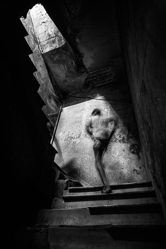 Two boys rapidly climbing the stairs of a dilapidated apartment building, San Lazaro street, Centro Habana district, Havana, Cuba. 2016