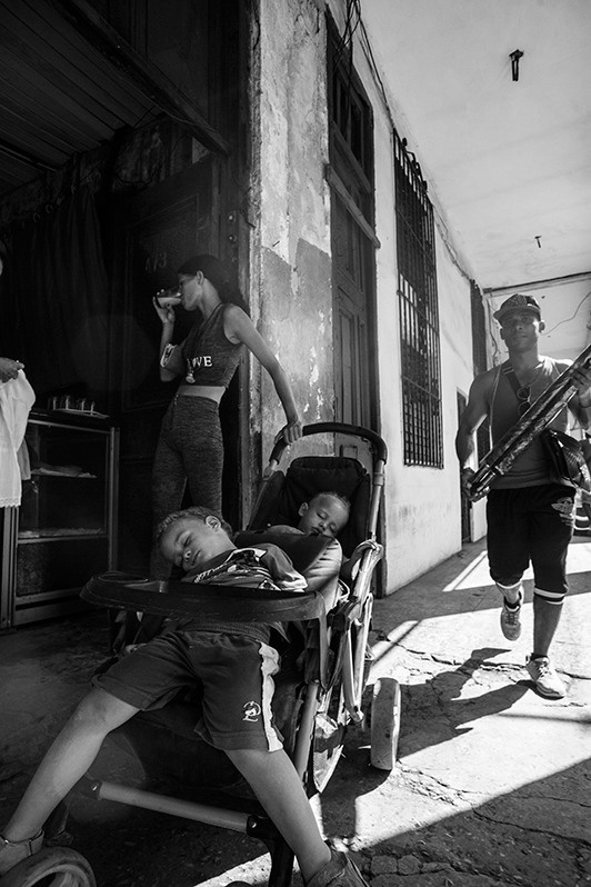 Cuban mum with two children taking a breather on a busy Monte street, Centro Habana district, Havana, Cuba. 2016