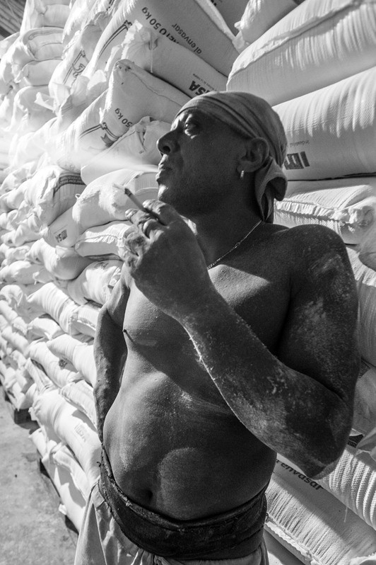 Worker with a cigarette during a smoke break in the warehouses with sacks of flour, Carlos III street, Centro Habana district, Havana, Cuba. 2016