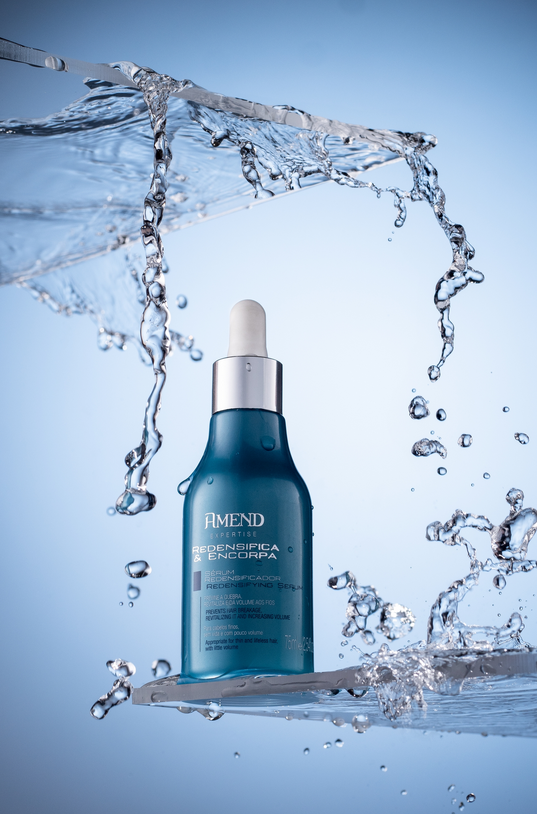 Blue glass perfume bottle with water splash — creative liquid motion product shoot.