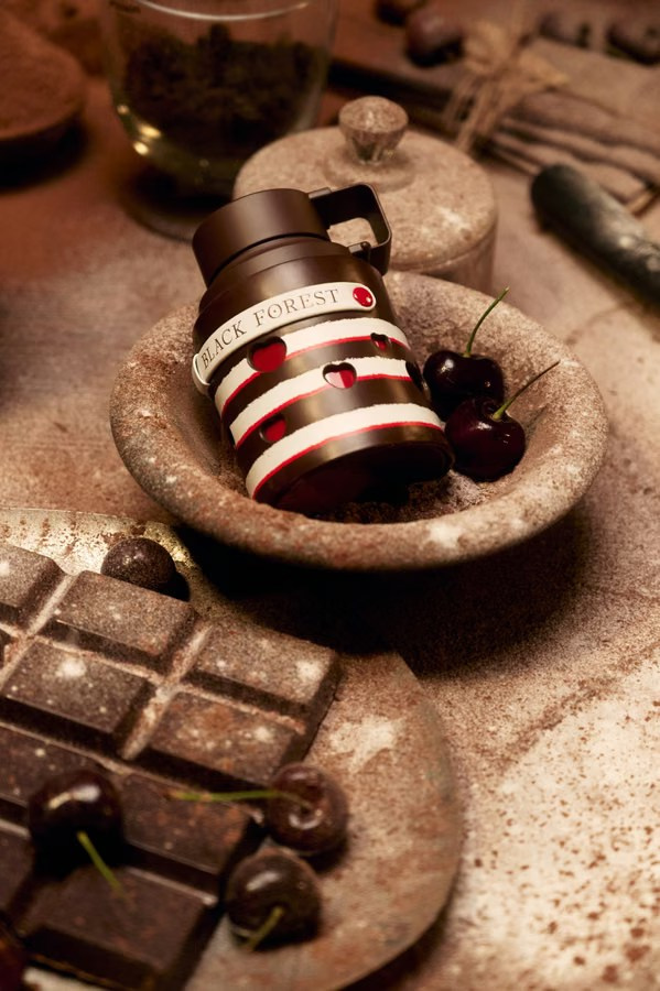 Dark perfume bottle styled with cherries and chocolate