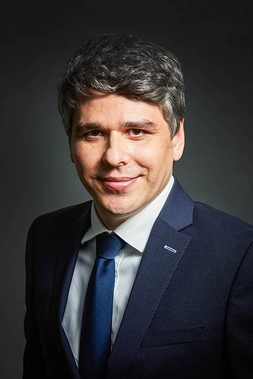 Business headshot against black background, on-location.