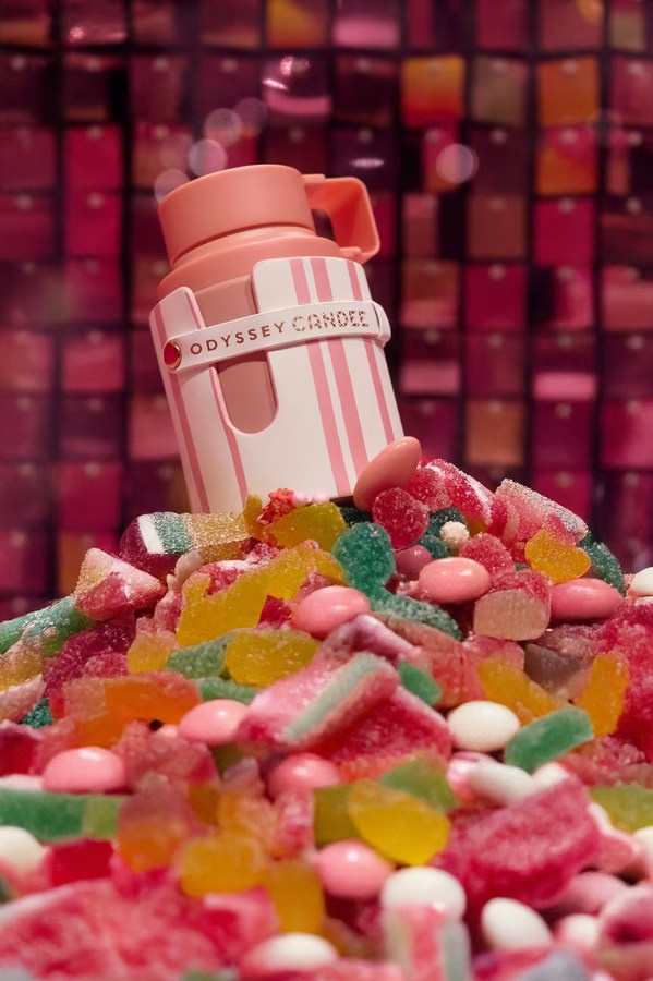 Playful product photography of a pink perfume bottle surrounded by bright jelly candies