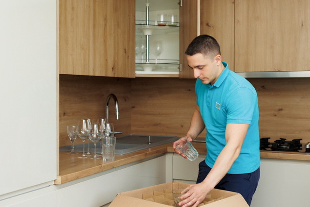 Un employé emballe des verres avec soin dans une cuisine