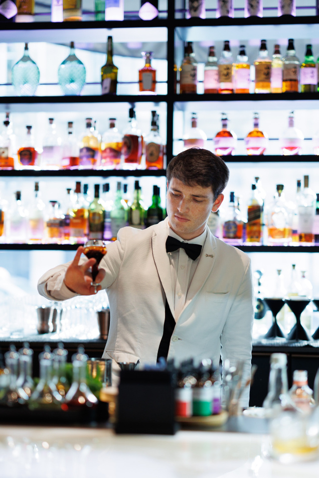 Barman en veste blanche servant un verre