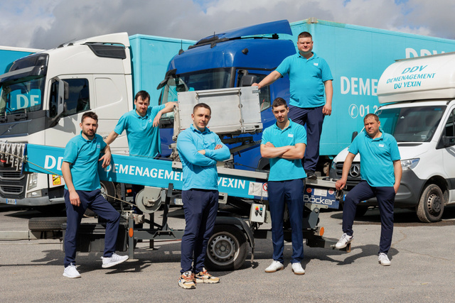 Six employés posent devant les camions de l'entreprise
