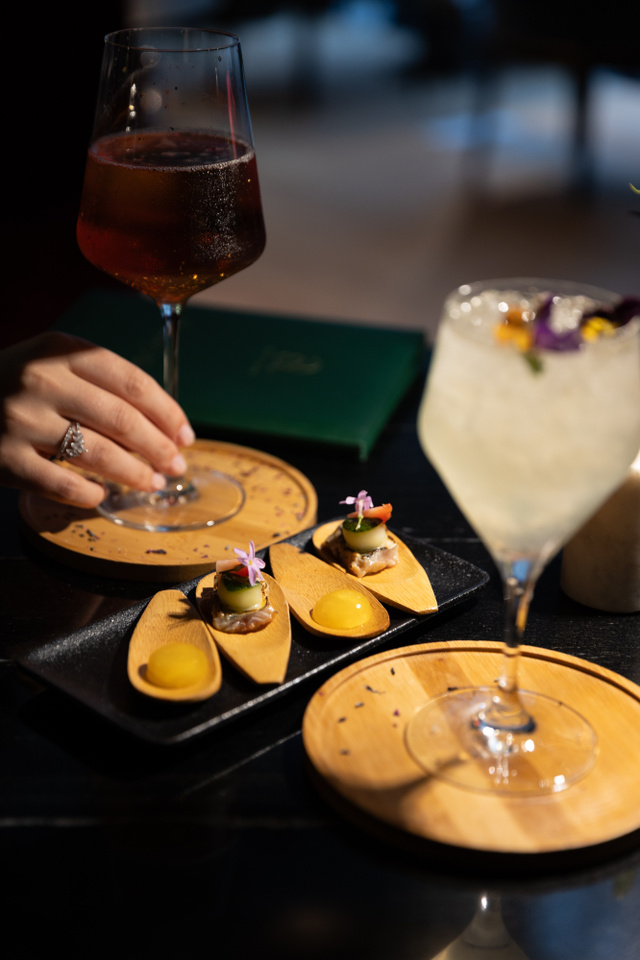Cocktail et bouchées servis au bar, main d'une cliente