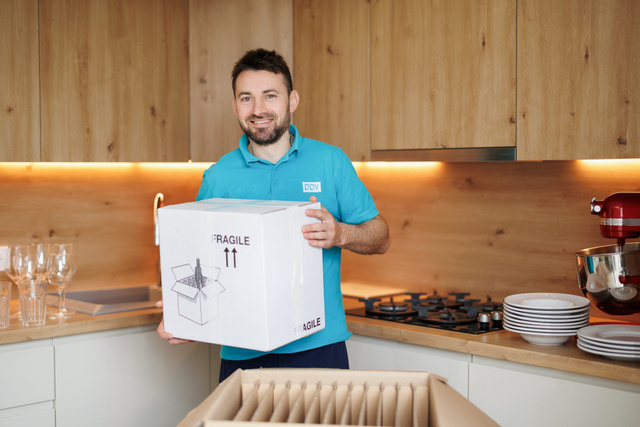 Un employé range un verre dans un carton de protection