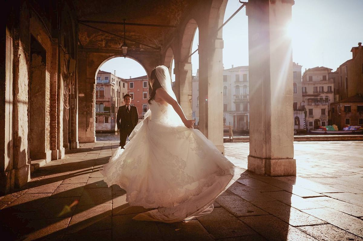Daisy spins in her wedding dress as Luis looks on, the sun flares vividly around her.