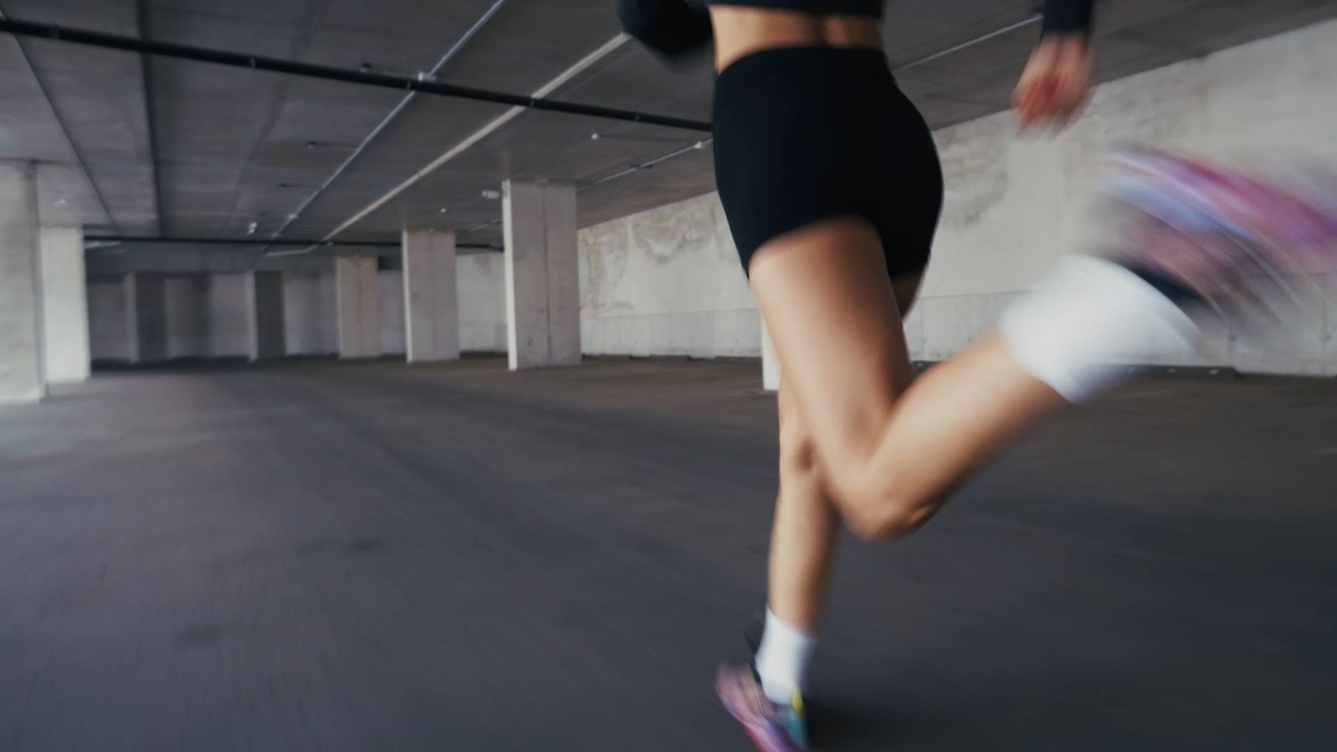 A blurred motion shot of a person running in a modern, industrial space, emphasizing speed and energy.