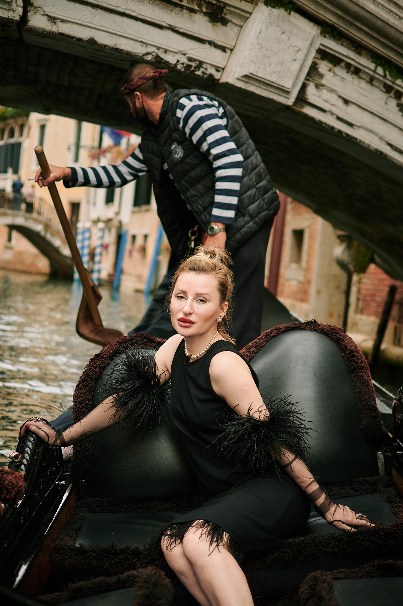 portrait photoshoot of woman in black, ride on gondola with gondolier in Venice. Fashion blogger shoot Venice. Portrait and Fashion Photographer in Venice, Italy. Instagram Photos with lifestyle photographer