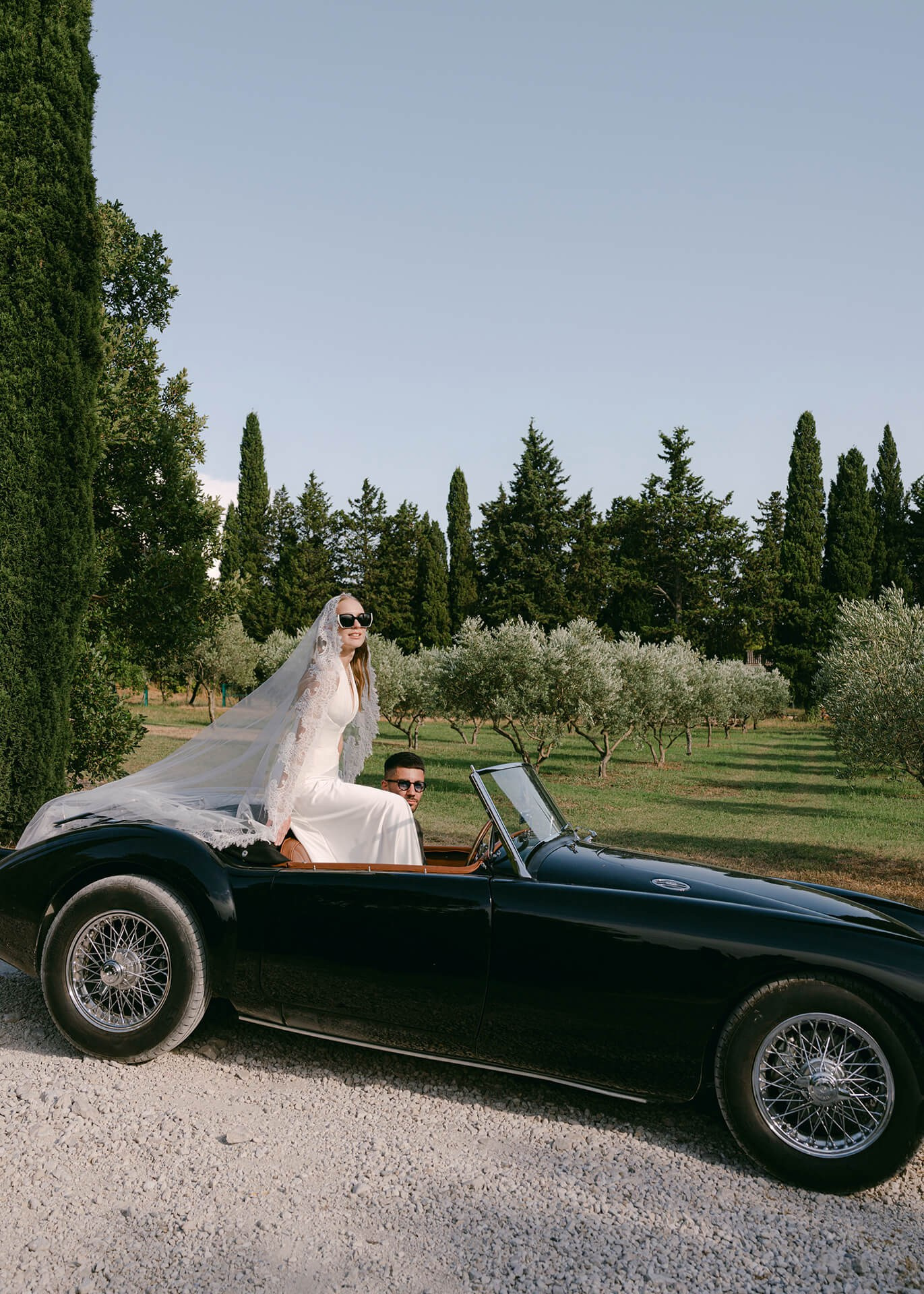 Bride in vintage convertible, editorial wedding portrait in olive grove