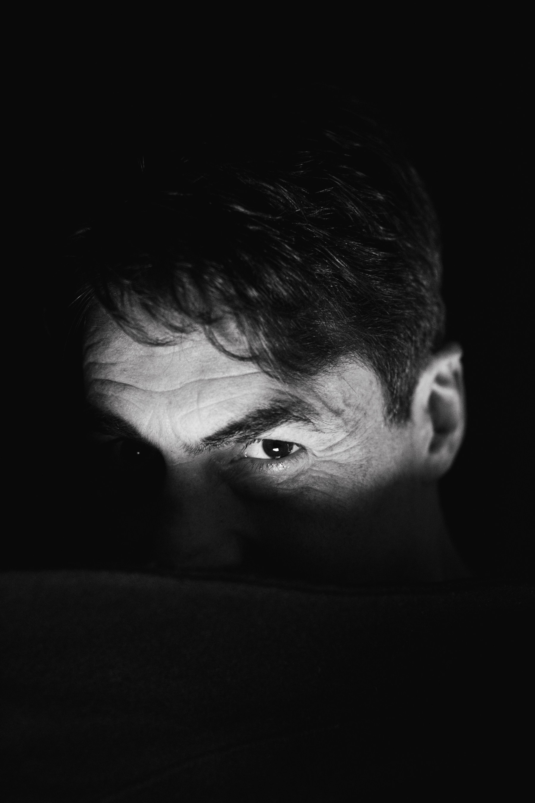 Fine art dramatic group portrait with motion blur, experimental black and white photography. Dramatic black and white portrait of a man looking from shadows, cinematic low-key lighting.
