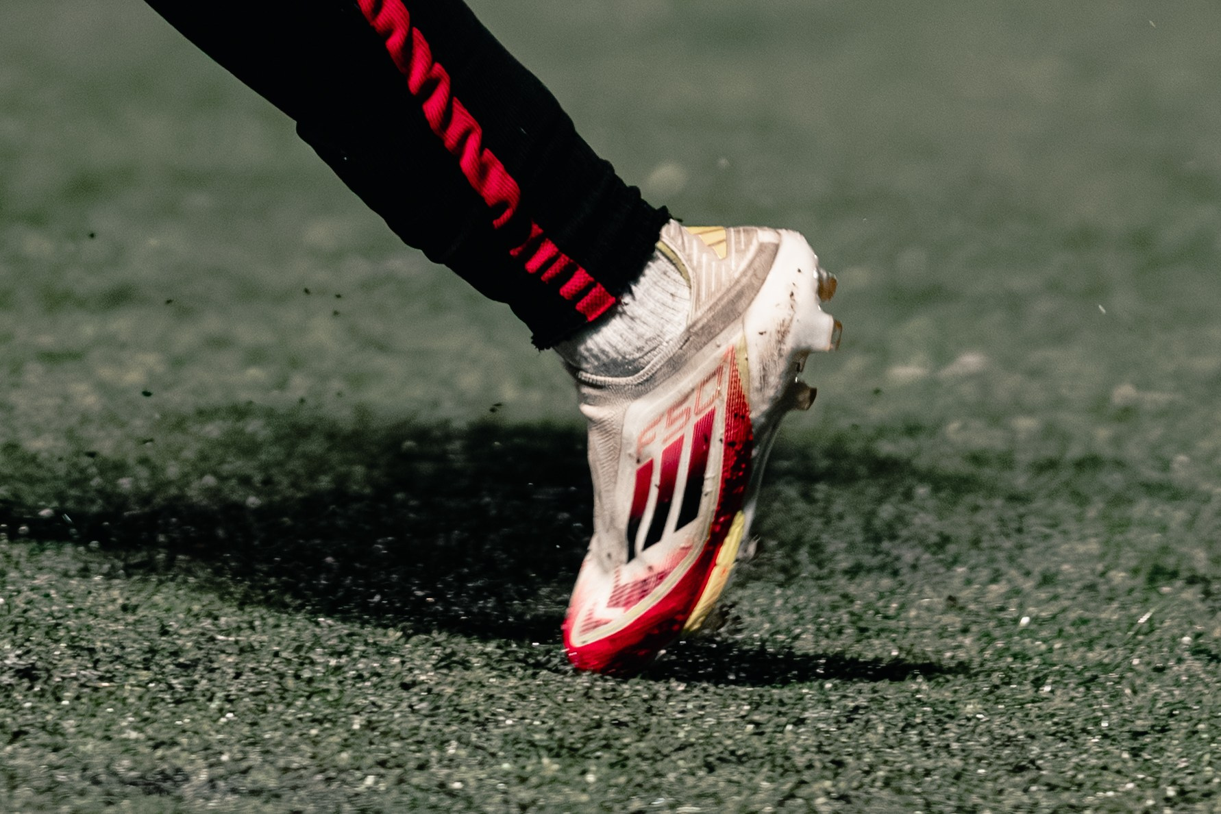Close-up of a football boot kicking up rubber pellets on a 3G pitch during Birmingham Senior Cup match between Tamworth and Alvechurch at The Lamb Ground, Feb 3 2026.