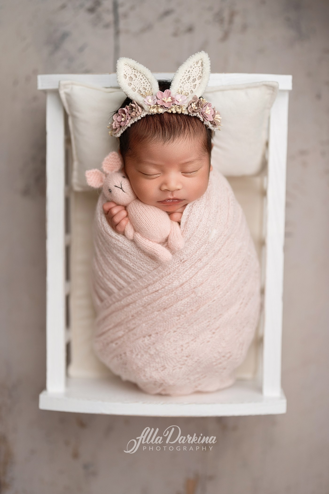 Sleeping newborn baby girl wrapped in soft pink fabric during a professional newborn photography session in Kellyville, Sydney.