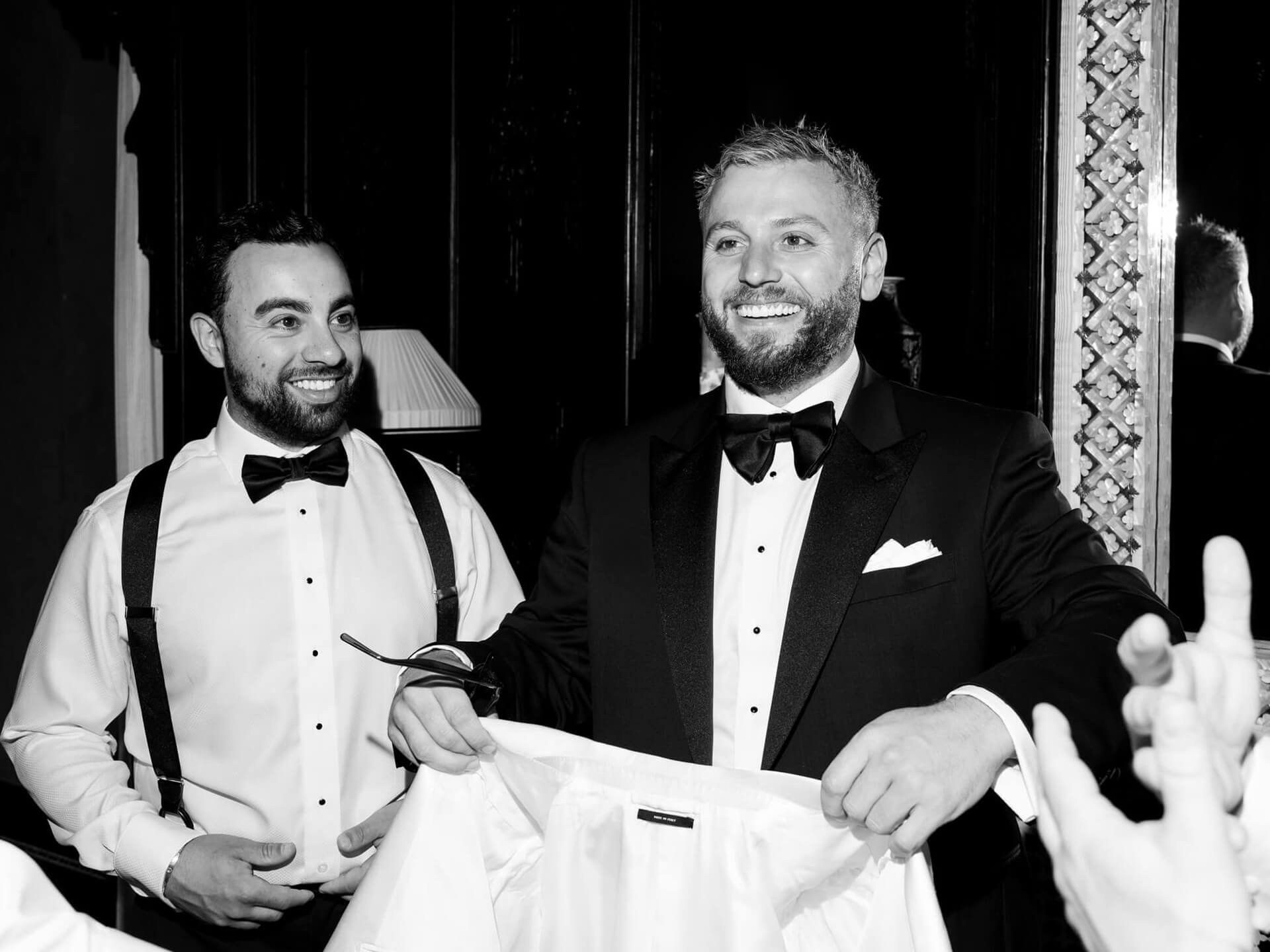 Groom holding shirt with friend at Villa Sola Cabiati