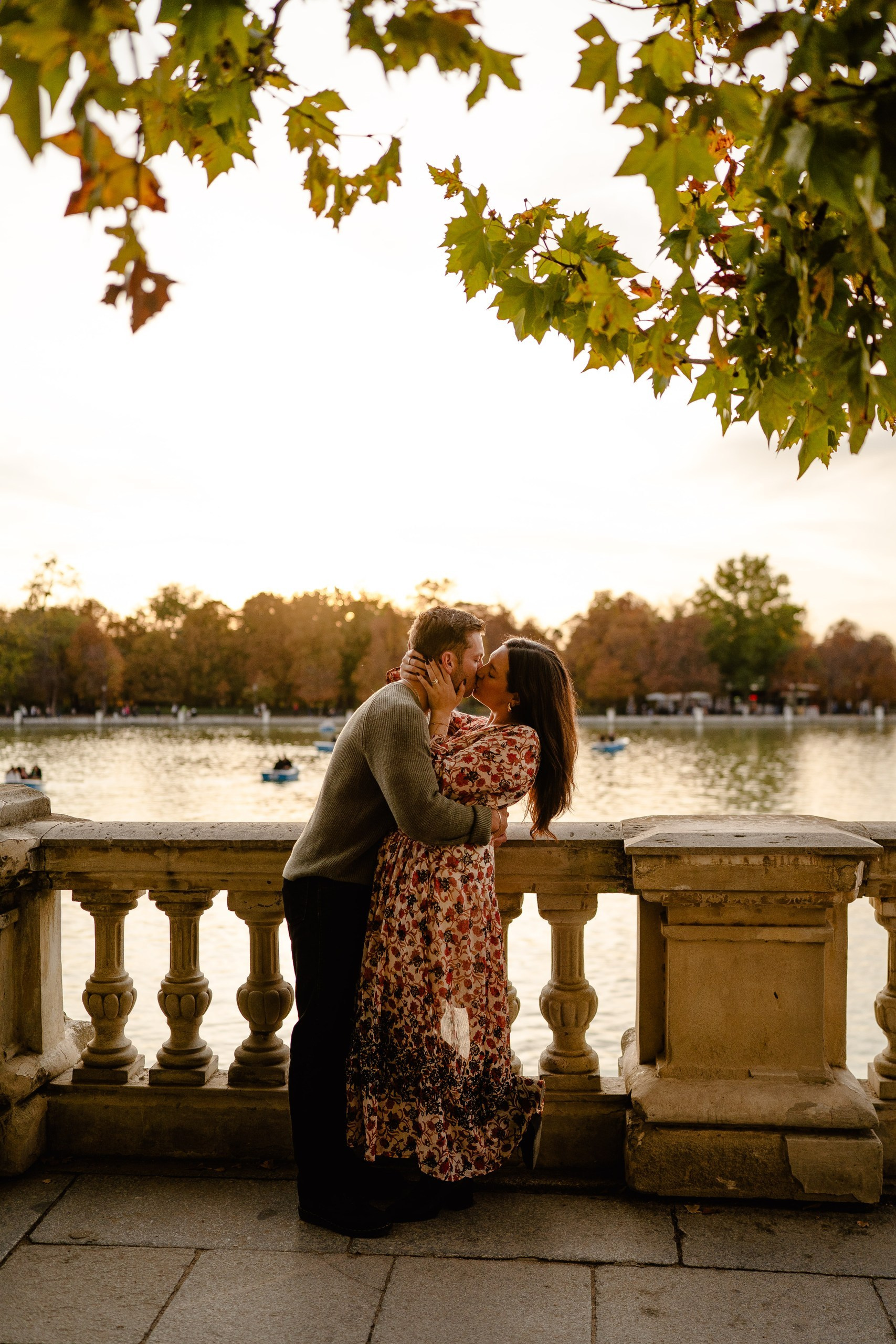 A couple hugging in Retiro Park during a dramatic sunset in Madrid.