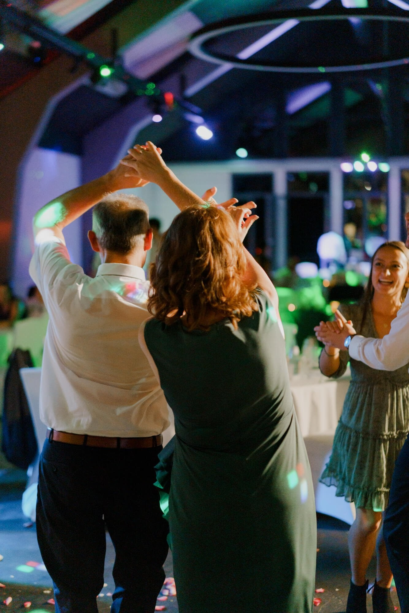Guests dancing energetically under colourful DJ lights at the Stuttgart wedding reception, the full dance floor alive behind them