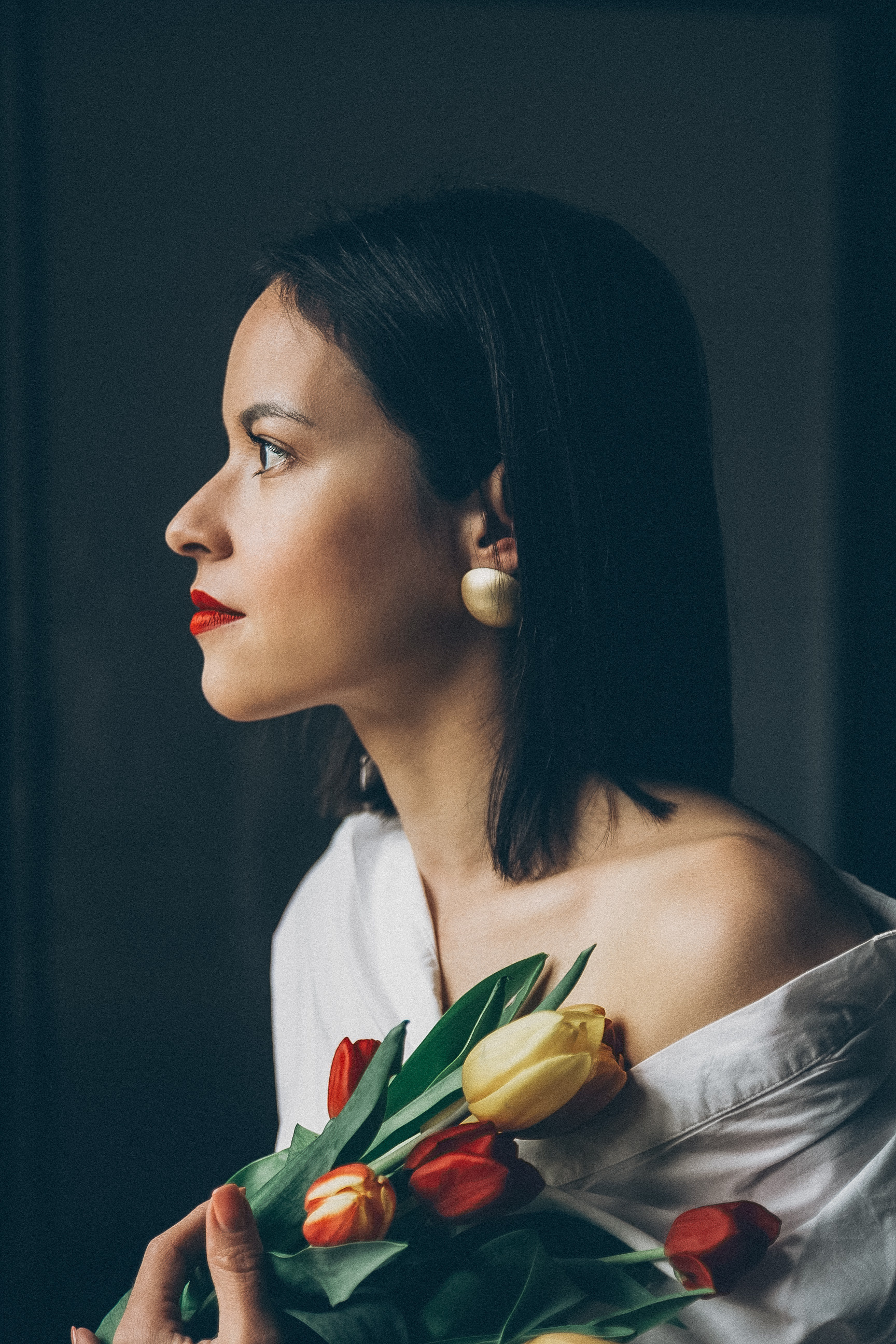 Stilvolles Portrait einer Frau mit Tulpenstrauß am Fenster – emotionale Einzelfotografie mit natürlichem Licht in Nürnberg.