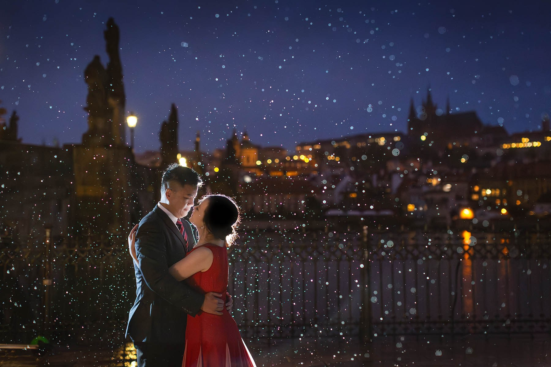 Justine and Robinson embrace near the Charles Bridge during a rainy twilight, Prague pre-wedding photography