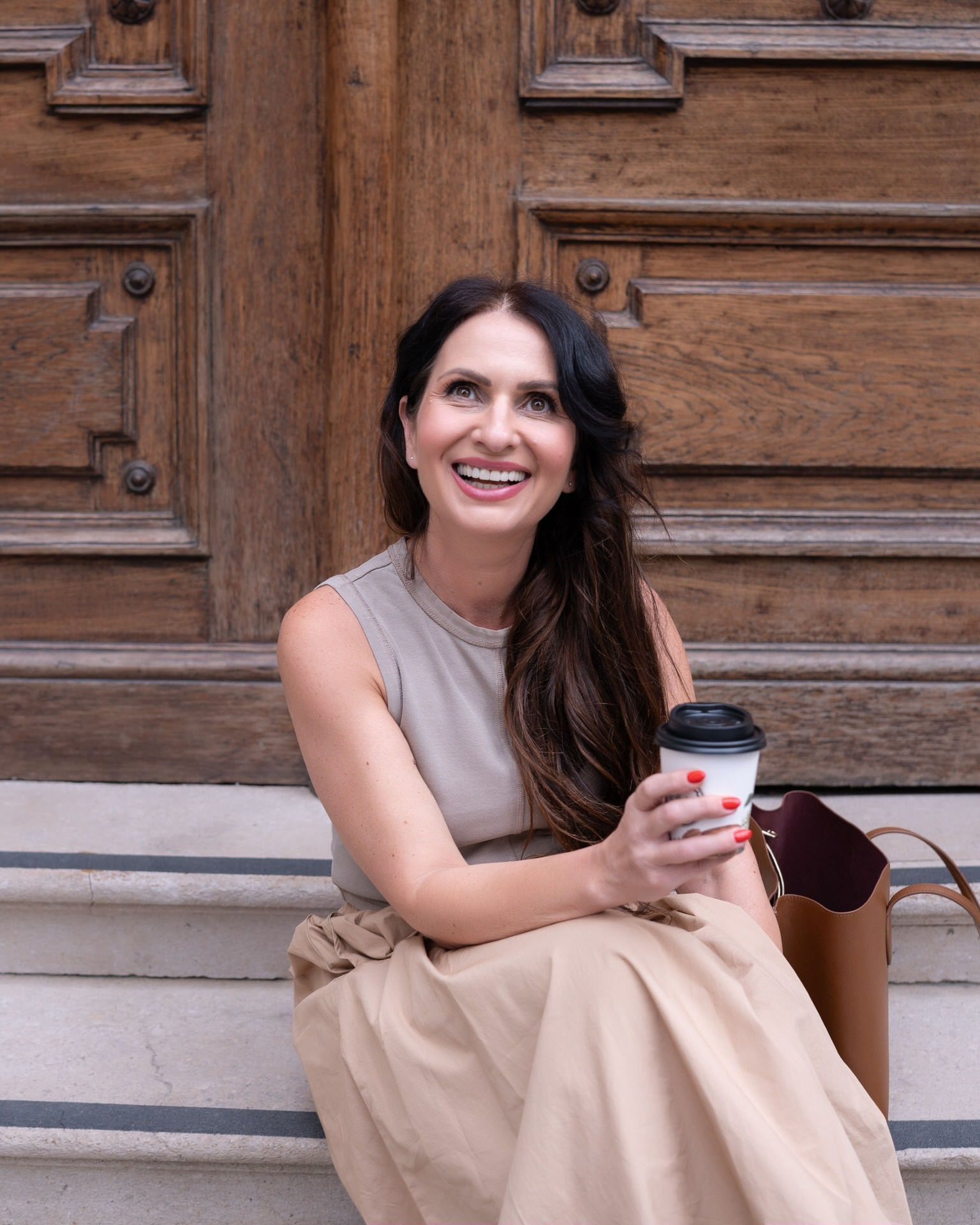 Snežana Markovič sedi sa šoljicom kafe za poneti na stepeništu i smeška se zadovoljno tokom snimanja za brend ffotografisanje za Copy radionicu