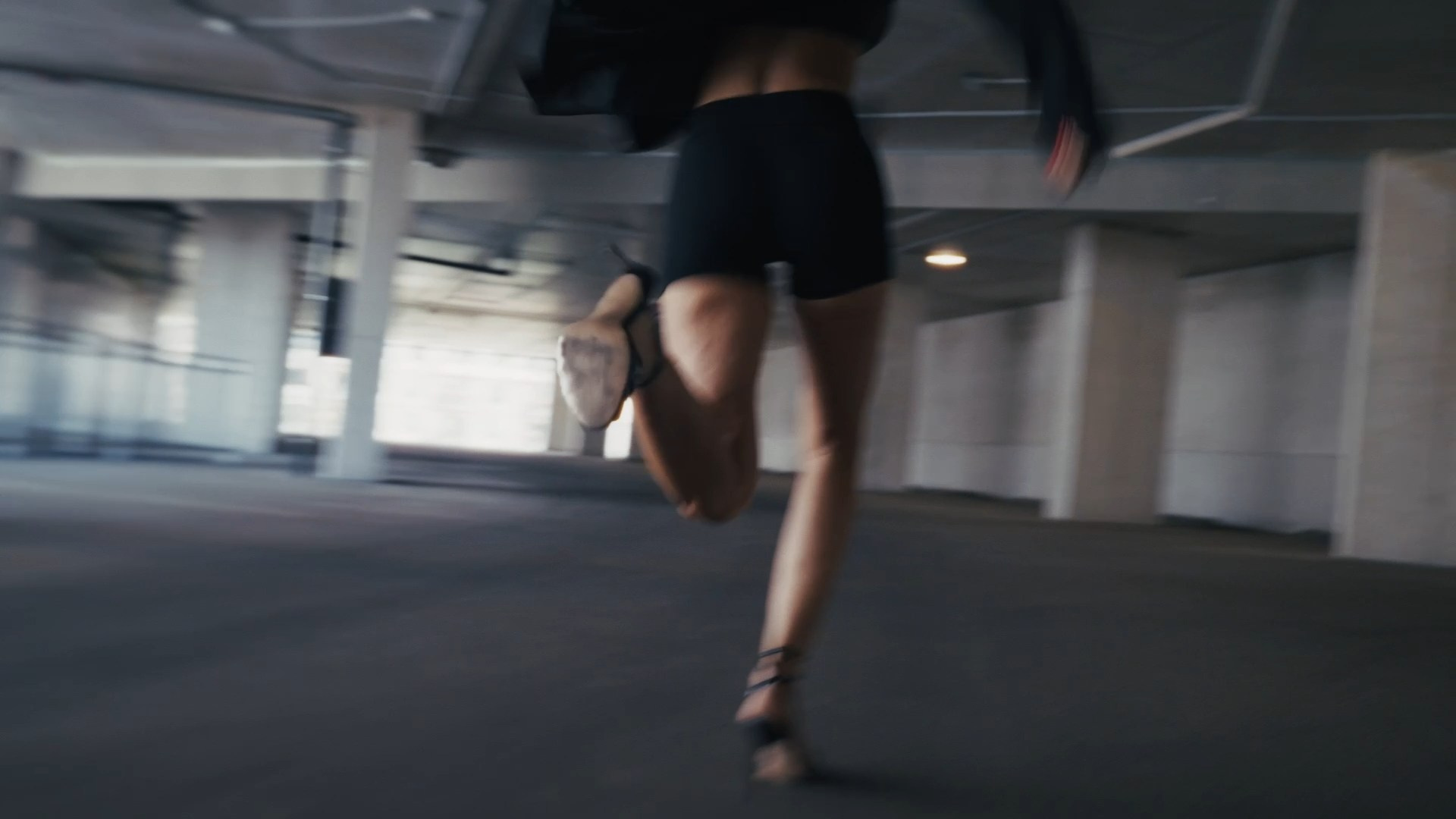 A blurred motion shot of a person running in a modern, industrial space, emphasizing speed and energy.