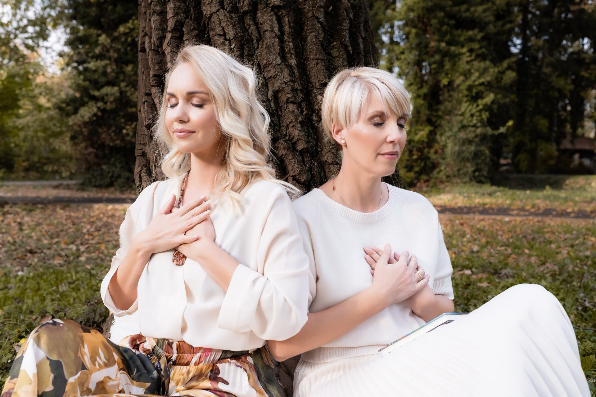 dve žene sede nalsonjene o drvo i meditiraju