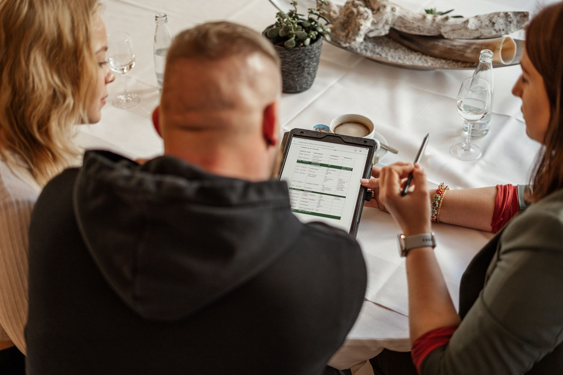 Hochzeitsplanung:Planungsdetails einer Hochzeit mit Notizblock, Kalender und Blumenarrangement im Hintergrund.