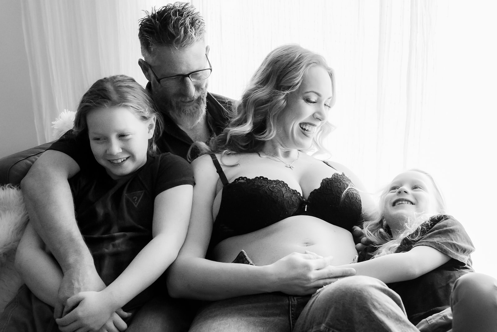 FAMILY OF FOUR. MOTHER IS PREGNANT AND HOLDING HER TWO SONS AND HUSBAND LOOKS AT THEM