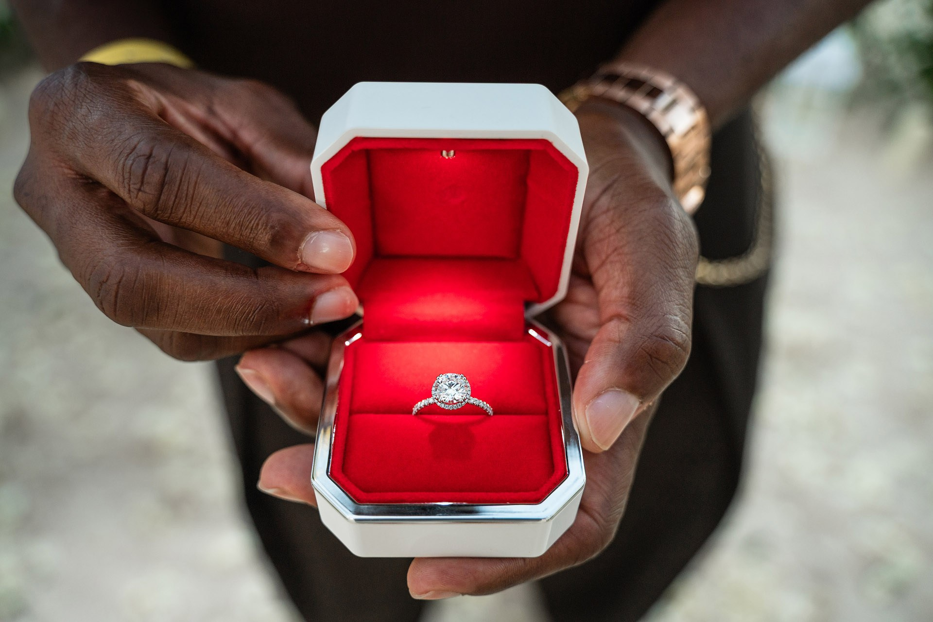 Man placing an engagement ring on his partner's finger inside a romantic white rose heart on Arena Gorda Beach.