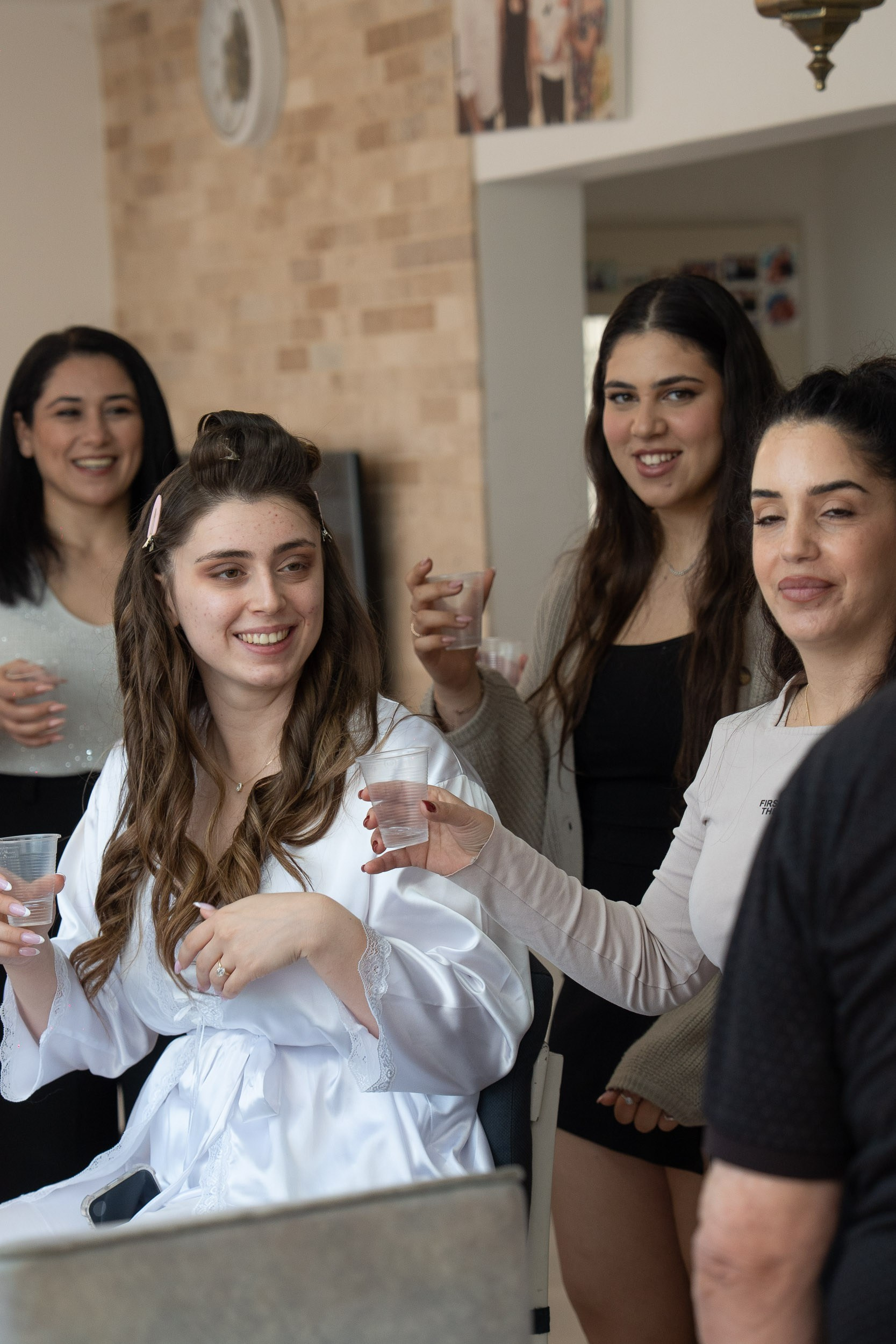 Bride Tzipi celebrating and laughing with her bridesmaids during morning preparation in Hadera, Israel