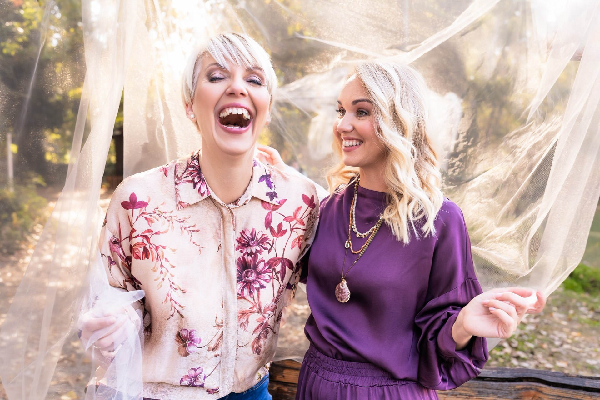 dve žene se smeju, jedna gelda u drugu, a druga u fotoaparat iza njih je mladenački veo