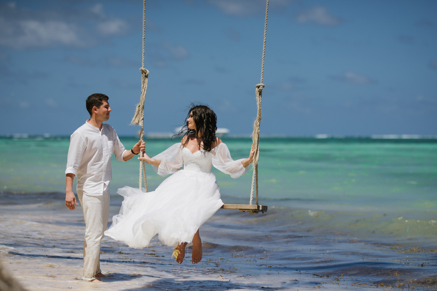Жених раскачивает качели с невестой. 