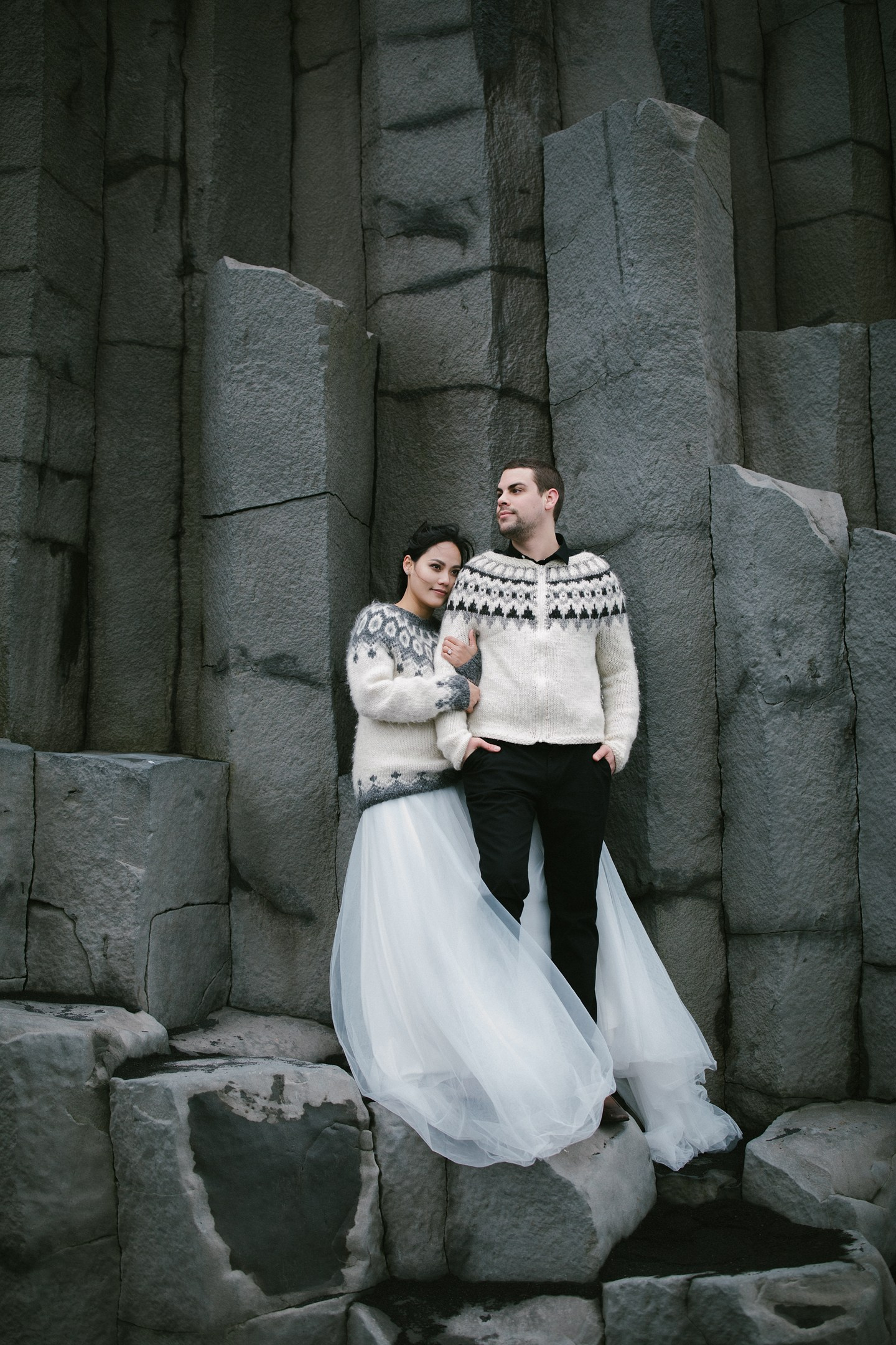 Couple in Icelandic sweaters by basalt columns