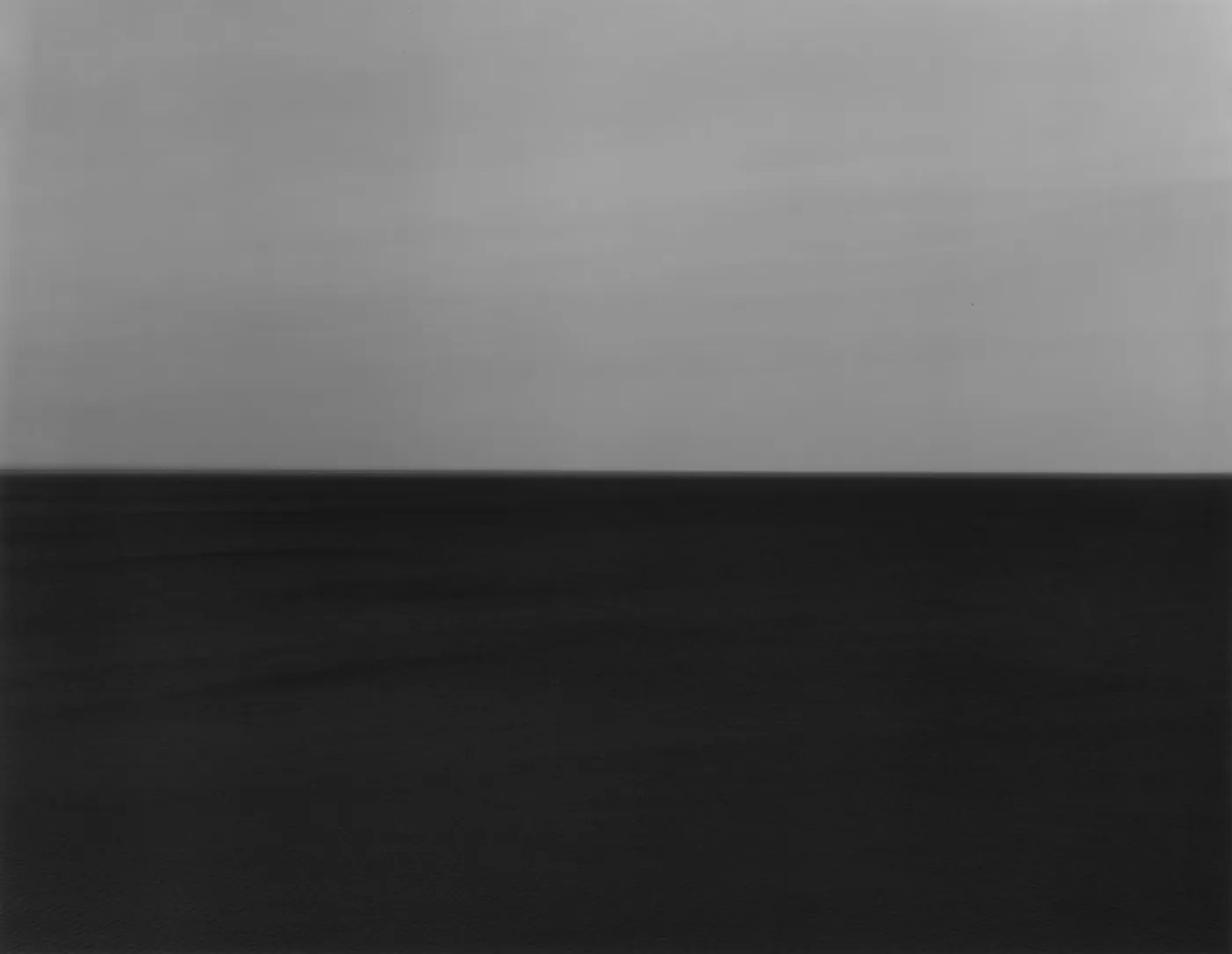 Длительные экспозиции стирают движение: море превращается в ровную горизонталь, а целый фильм — в один ослепительно белый кадр. Время исчезает в длительности.