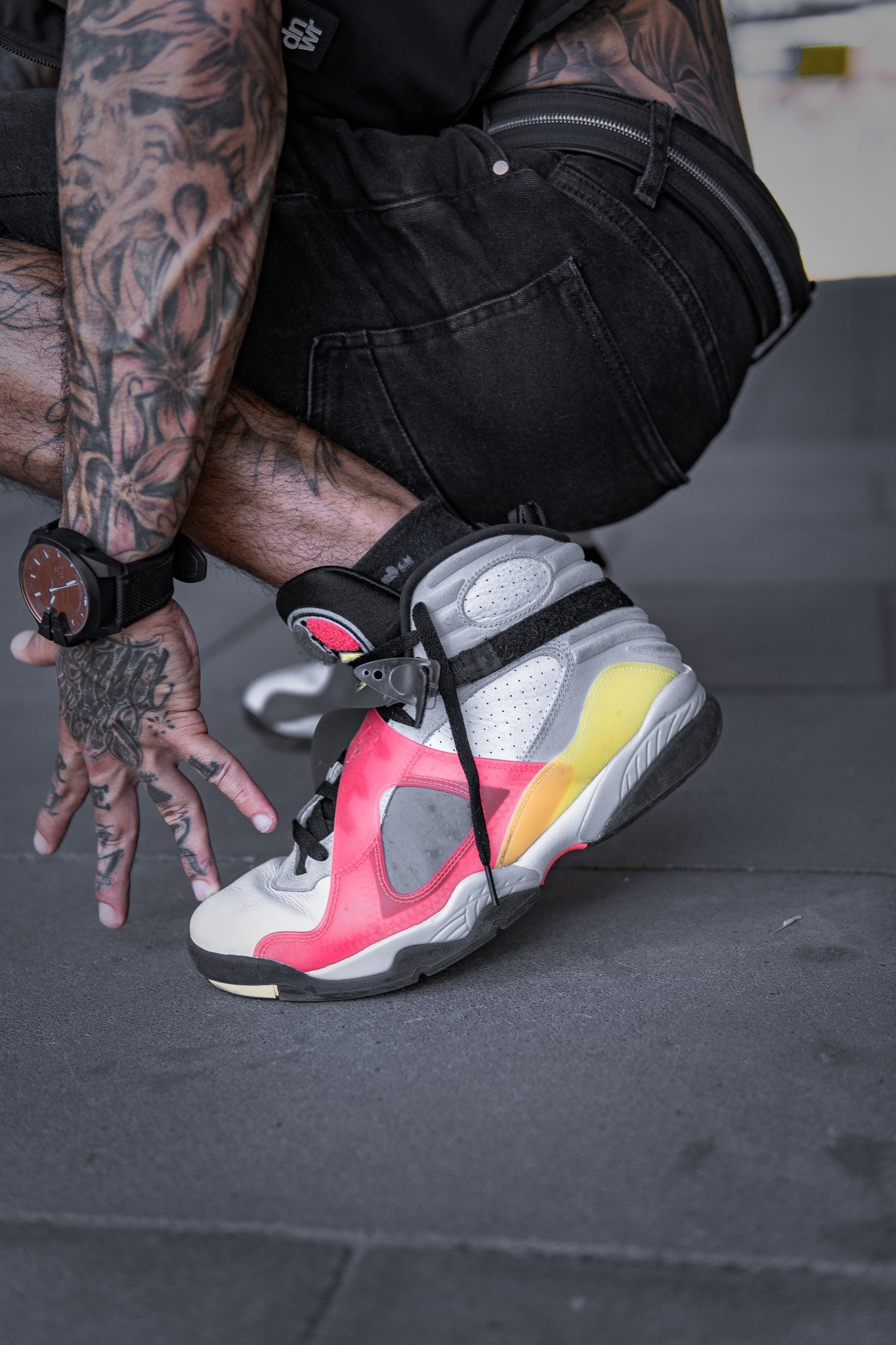 Zapatillas de colores calzadas sobre suelo oscuro de estudio
