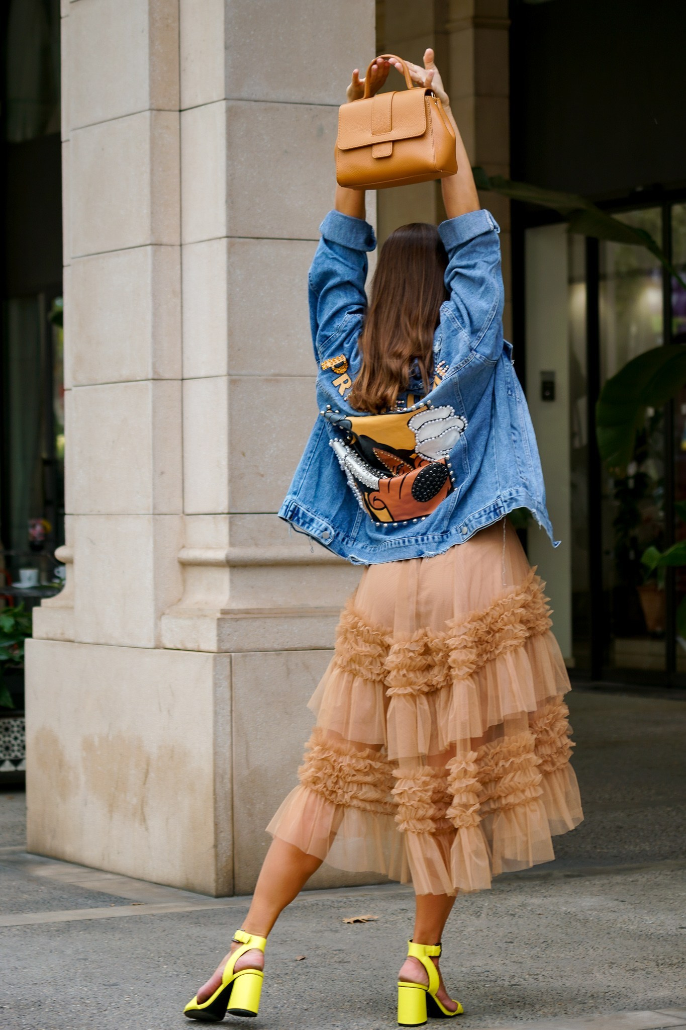Modelo con falda de volantes y bolso azul en unas escaleras