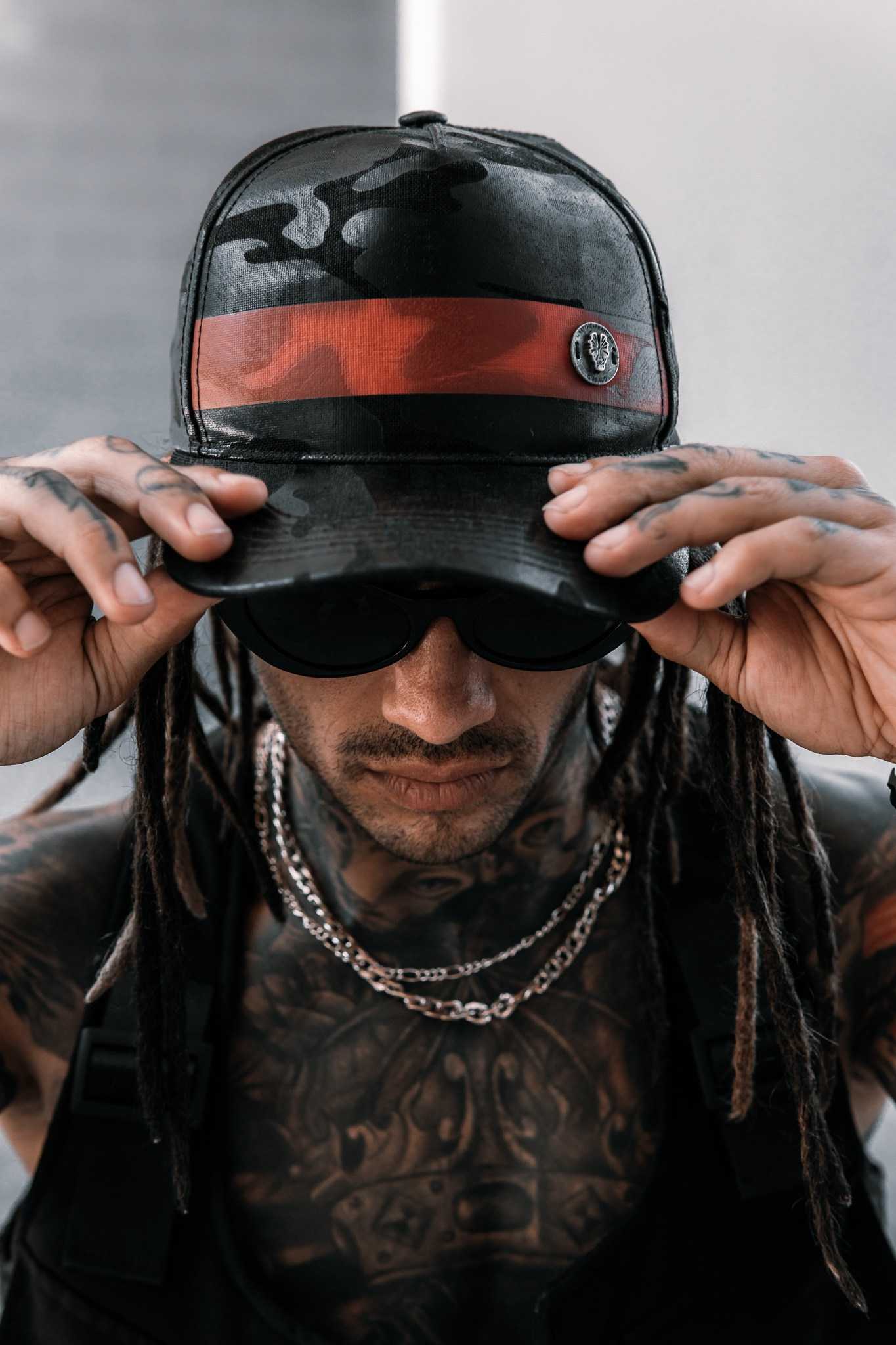 Modelo ajustándose una gorra, cadenas superpuestas visibles