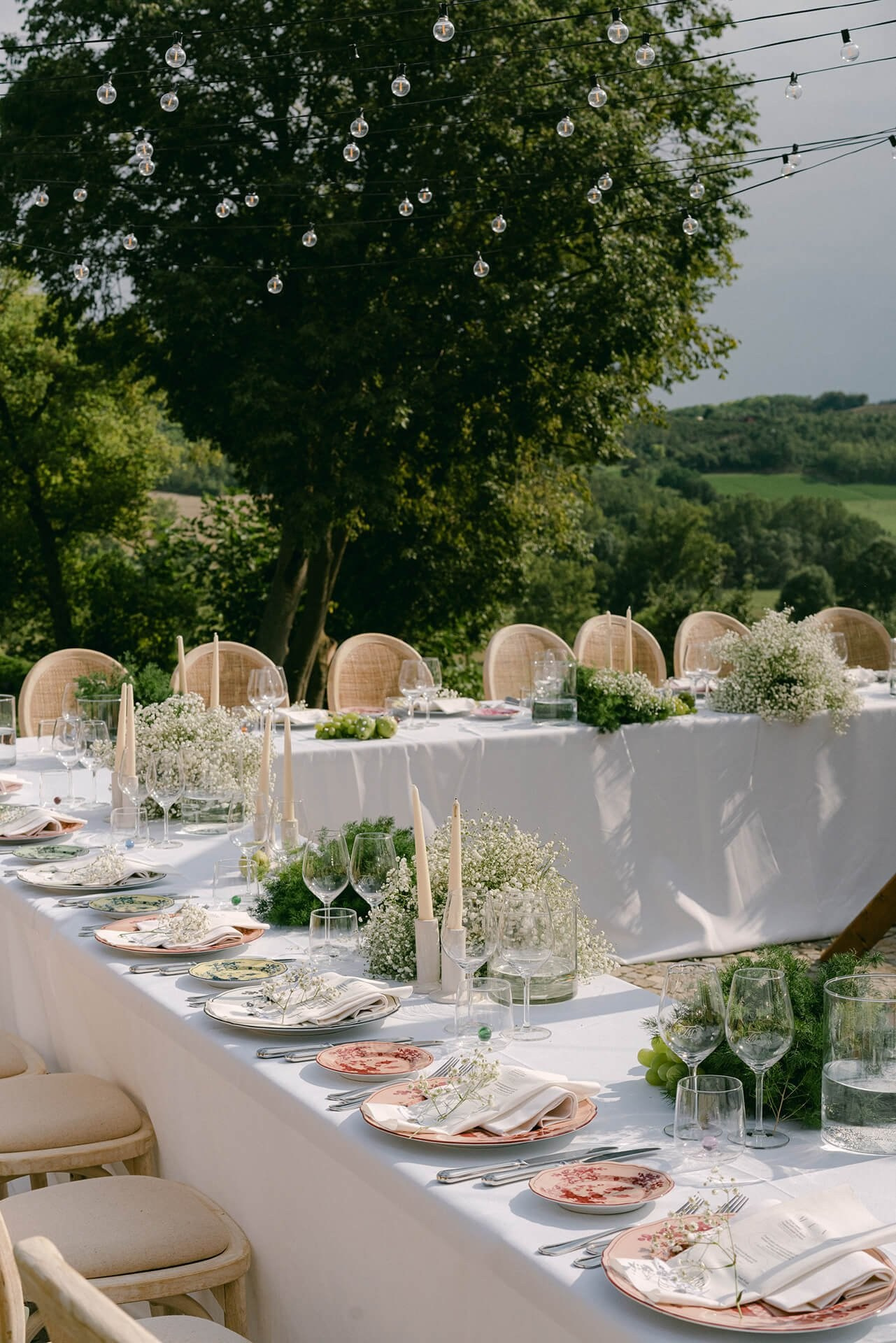 Wedding reception table under string lights, baby’s breath florals