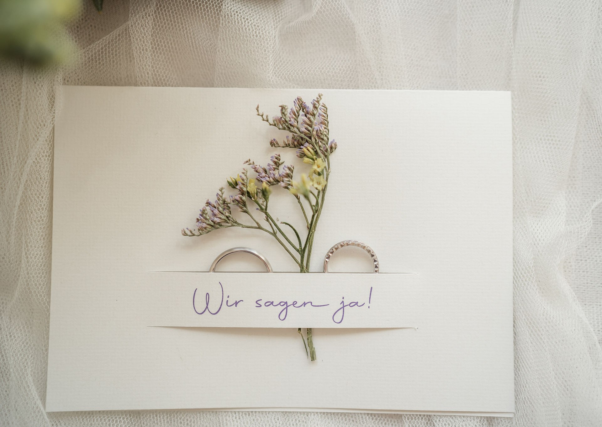„Elegante Hochzeitseinladungskarten mit floralen Designs und handgeschriebener Schrift auf einem Holztisch.“