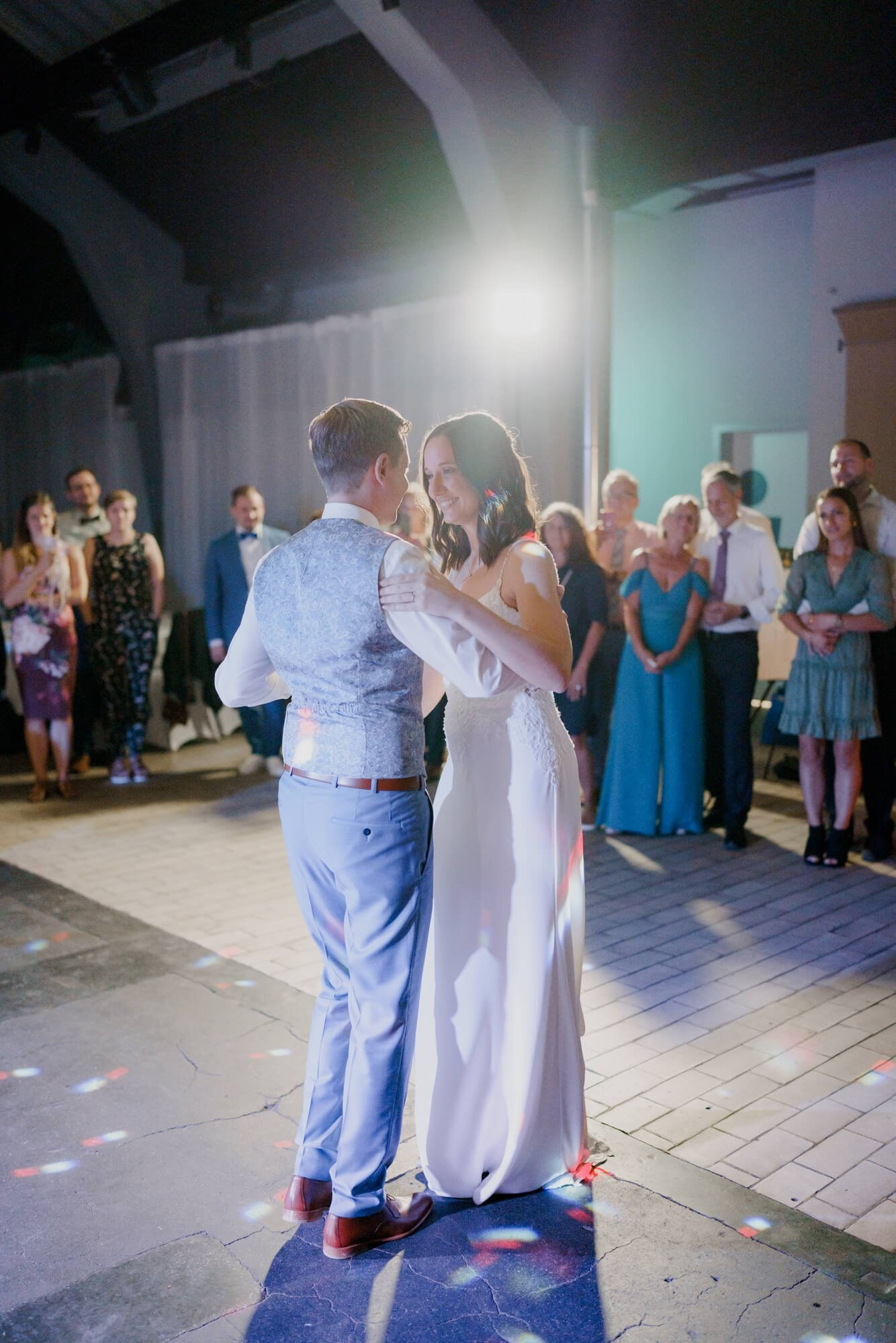 Newlyweds seen from behind during their first dance at the Stuttgart wedding reception, guests forming a circle around them