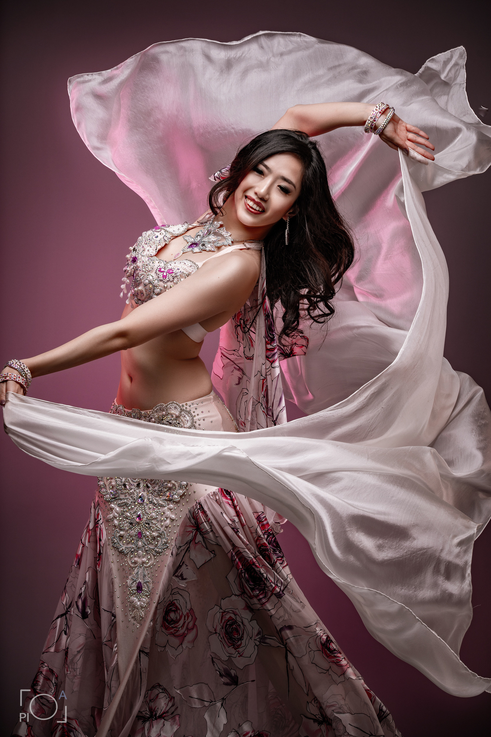 Chic female belly dance dancer. Fabric developing around, studio photo shoot for charming Chinese woman.
