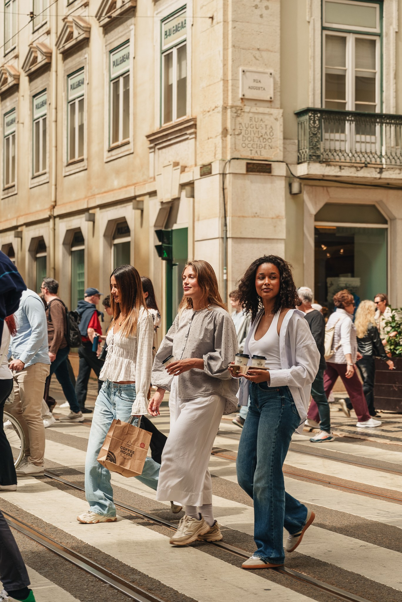 Fotografia lifestyle e de moda de três mulheres a caminhar numa passadeira de cidade ao sol, captada pela Khave Media em Lisboa, Portugal