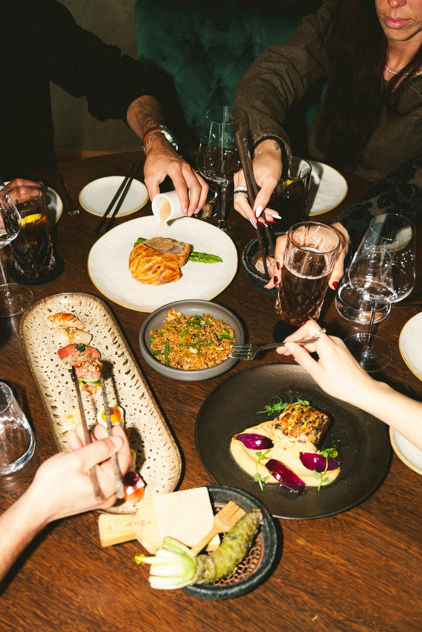 Fotografia de gastronomia e lifestyle vista de cima, mostrando um grupo de pessoas a partilhar vários pratos e bebidas num restaurante no norte de Portugal