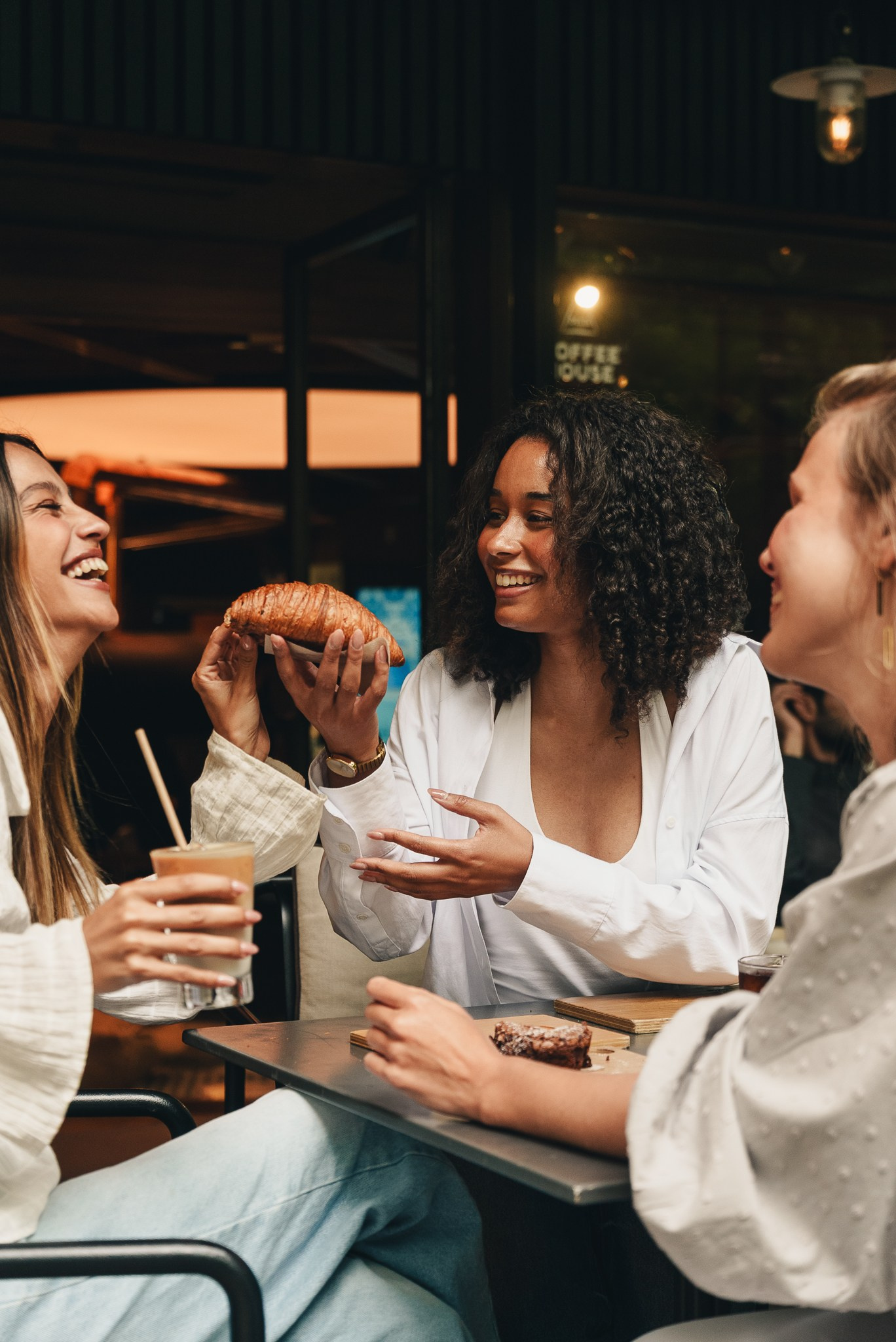 Fotografia de lifestyle e restauração de três mulheres a sorrir e a conversar à mesa num bar ou restaurante, produzida pela empresa de fotografia Khave Media